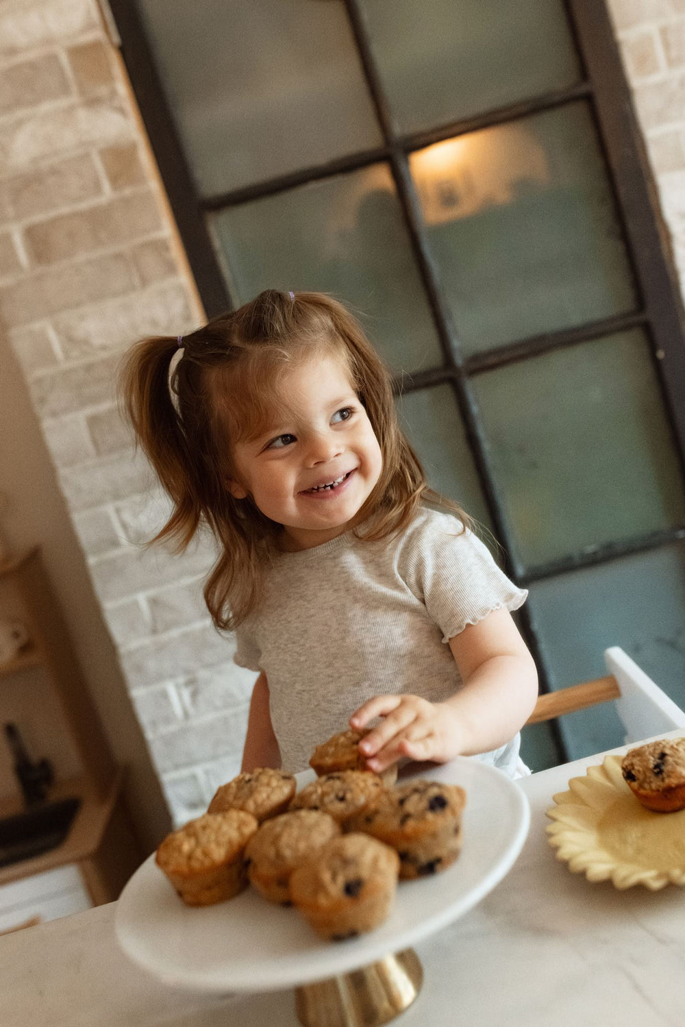 A toddler reaching for a plate of Little Summer Club pancakes